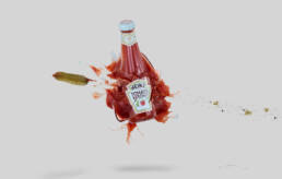 Heinz ketchup bottle smashing in mid air with gherkin