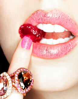 Model eating cherry garnish wearing oversized cocktail rings
